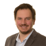 man with dark hair and beard smiling at camera