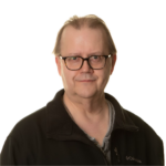 Man with dark hair and glasses smiling at the camera