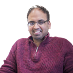 Man with shirt hair and glasses smiling at camera.