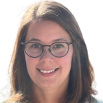 Woman with glasses and long dark hair smiling at camera.